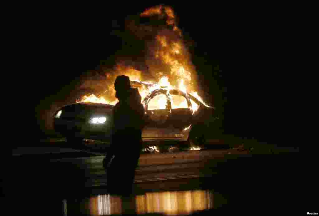 Sebuah mobil terbakar di jalan menyusul demonstrasi yang memprotes keputusan pengadilan untuk tidak mendakwa polisi Darren Wilson dalam penembakan fatal atas Michael Brown, remaja 18 tahun berkulit hitam tak bersenjata, di Ferguson, Missouri (24/11). (Reuters/Jim Young)