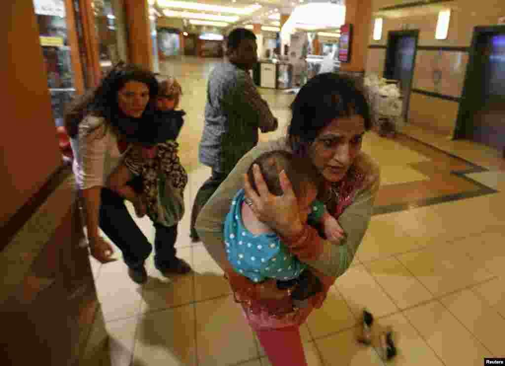 Women carrying children run for safety as armed police hunt gunmen at the Westgate Mall in Nairobi, Sept. 21, 2013.