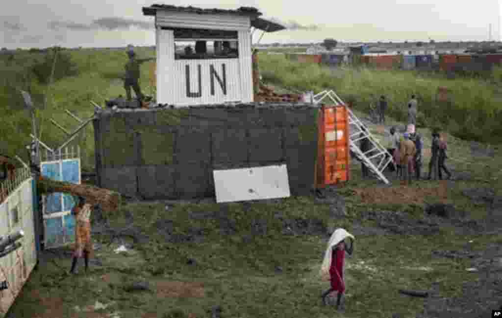 Les déplacés sud-soudanaises quittent le camp pendant la journée pour ramasser du bois et d'autres produits, à côté des casques bleus en provenance de Mongolie qui gardaient la porte, dans un camp de fortune pour personnes déplacées situé dans le village de Bentiu, au Soudan du Sud.