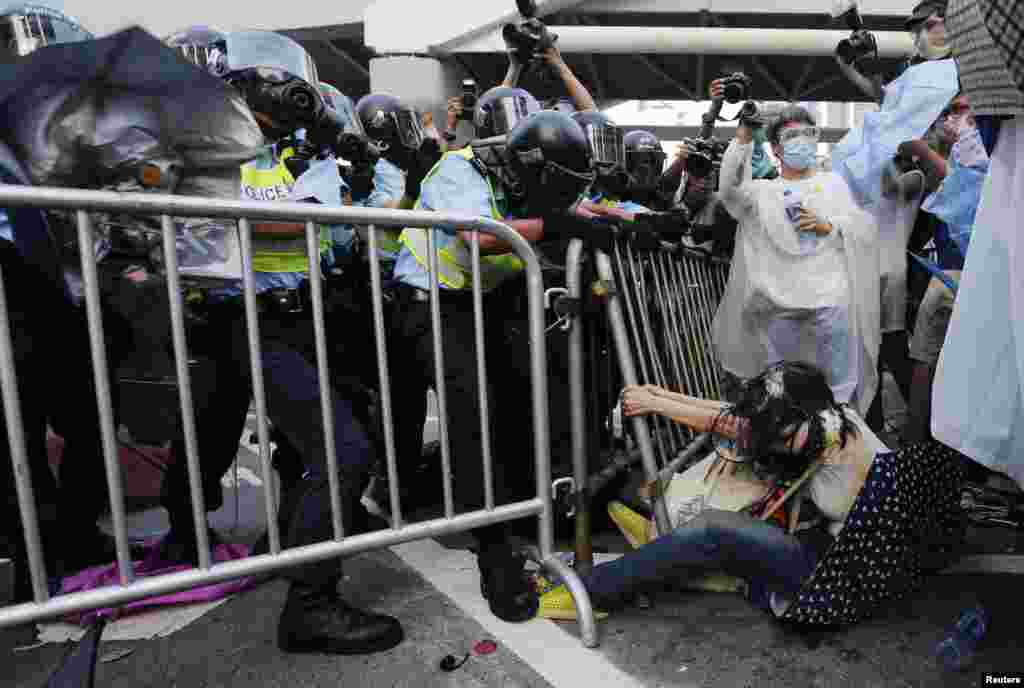 A woman (bottom R) on the ground holds on to a fence during a clash with riot policemen outside the government headquarters in Hong Kong.