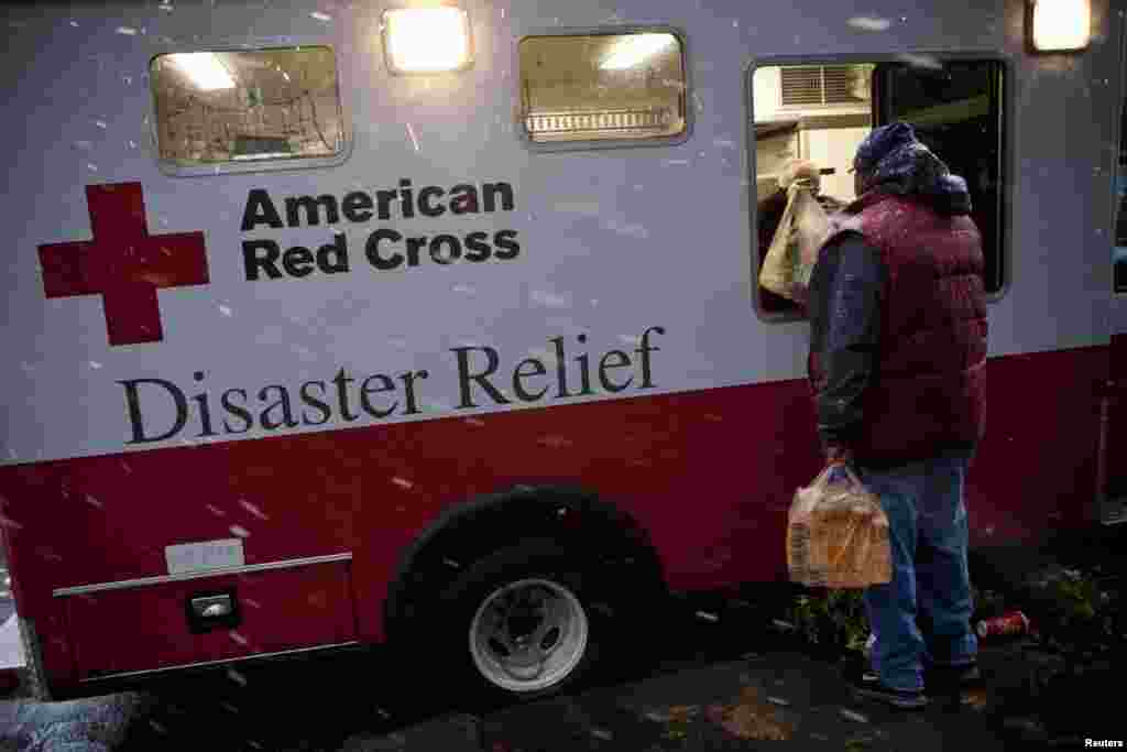 A victim of Hurricane Sandy receives a meal from an American Red Cross Disaster Relief truck during a nor'easter, also known as a northeaster storm, in the Red Hook Neighborhood of New York, November 7, 2012.