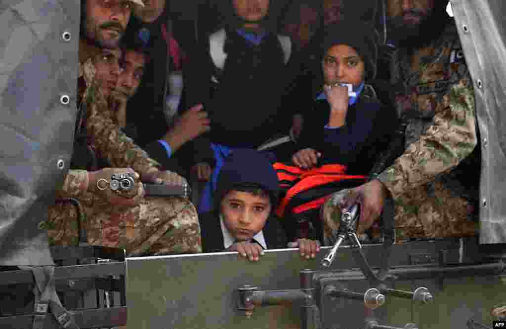 Des soladts pakistanaise transportent des élèves qui ont échappé à l'attaque d'uune école par des hommes armés talibans à Peshawar le 16 décembre 2014.