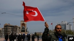 A supporter of Turkey's main opposition Republican People's Party, CHP, waves a national flag as people gather for a sit-in protest in central Istanbul's Taksim Square, Monday, April 16, 2018.