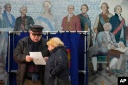 Masyarakat memeriksa surat suara di TPS yang terletak di sebuah sekolah saat pemilihan presiden di St. Petersburg, Rusia, Sabtu, 16 Maret 2024, (Foto: AP)