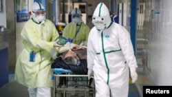 Para petugas medis dengan pakaian pelindung membawa pasien di ruang isolasi di distrik Caidian menyusul wabah virus novel korona di Wuhan, Provinsi Hubei, China, 6 Februari 2020. (Foto: Reuters)
