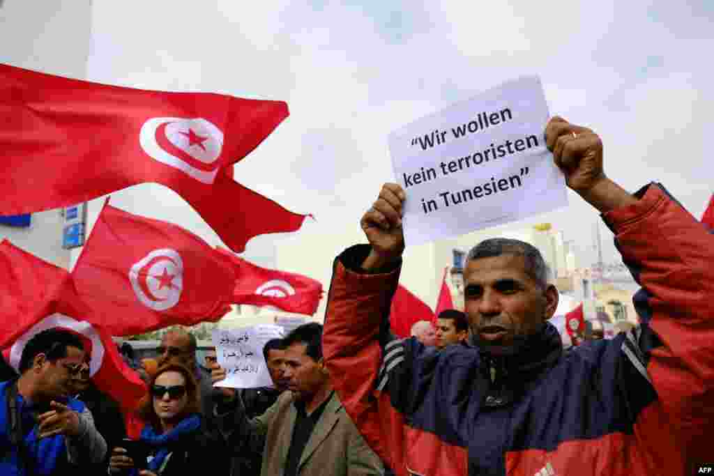 Warga Tunisia melambaikan bendera pada sebuah demonstrasi di Midoun, sebelah barat laut Djerba, dua hari setelah pria-pria bersenjata menyerang Museum Nasional Bardo. Serangan tersebut menewaskan 21 orang, aksi kekerasan terparah di negara ini sejak penggulingan pemimpin Tunisia Zine El Abidine Ben Ali &nbsp;pada tahun 2011.